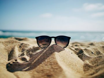 image of a beach and sunglasses in sand